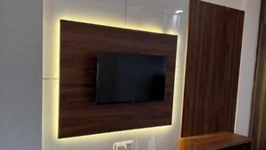 A modern entertainment unit with a flat-screen TV, integrated lighting, and a wooden bench.