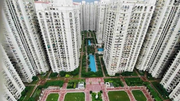 A high-rise residential building complex with multiple floors, a central courtyard with a swimming pool, and surrounding green spaces.