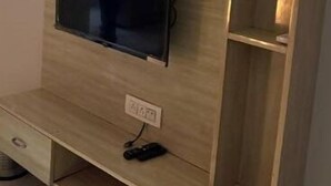 Un meuble de rangement en bois comprenant un téléviseur à écran plat, des étagères et une prise de courant.