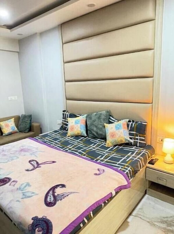 Un dormitorio con cama, mesita de noche y cabecero fijado a la pared.