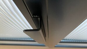 Un coin de pièce avec un plancher en bois et un objet noir, qui pourrait être un meuble.