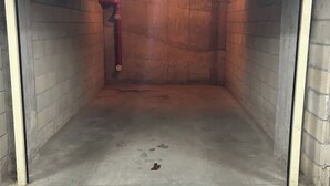 A room with brick walls, a concrete floor, and a red pipe running along one wall. - MarkApart 3: Apartment in Downtown Ruse (Ruse)