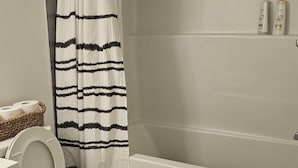 A bathroom with a toilet, a shower curtain, a bathtub, and a towel rack.