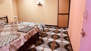 Un dormitorio con cama, mesita de noche, cómoda, lámpara de pared y suelo estampado.