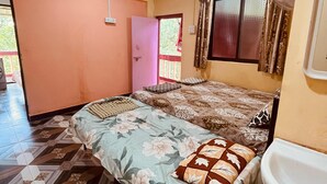 Una habitación con cama, ventana con cortinas, ventilador y lavabo.