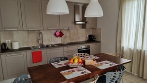 A modern kitchen with two pendant lights, a dining table with chairs, and a red towel hanging on the cabinet. - Villa for family/friends, few minutes from the most beautiful medieval villages (Umbria)