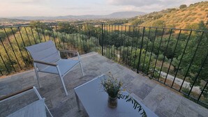 A balcony with a white chair and a table with a vase of flowers, overlooking a hilly landscape. - Villa for family/friends, few minutes from the most beautiful medieval villages (Umbria)