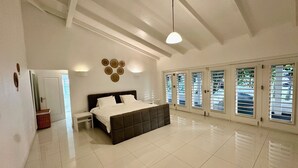 Un dormitorio amplio con una cama grande, una mesita de noche y una lámpara fijada a la pared.