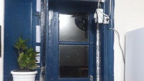 A small window with a blue frame, a potted plant on the windowsill, and a white air conditioning unit mounted above the window. - Hostel Sapucali (Rio de Janeiro)