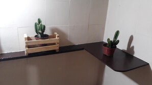 A corner of a room with a wooden crate holding a potted plant, a small potted plant on a black surface, and a white wall with a shadow. - Hostel Sapucali (Rio de Janeiro)