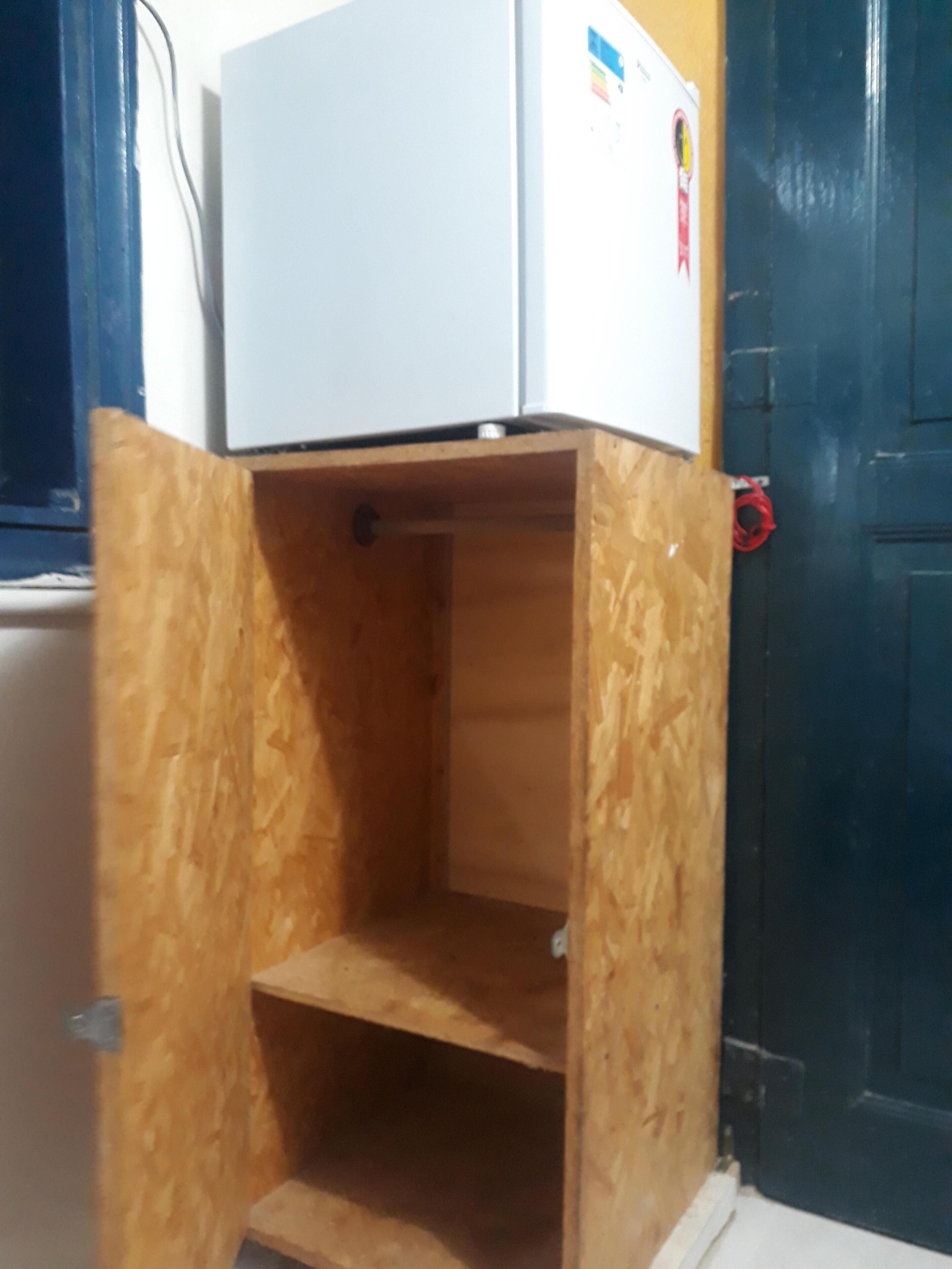A compact room with a wooden cabinet and a white refrigerator.