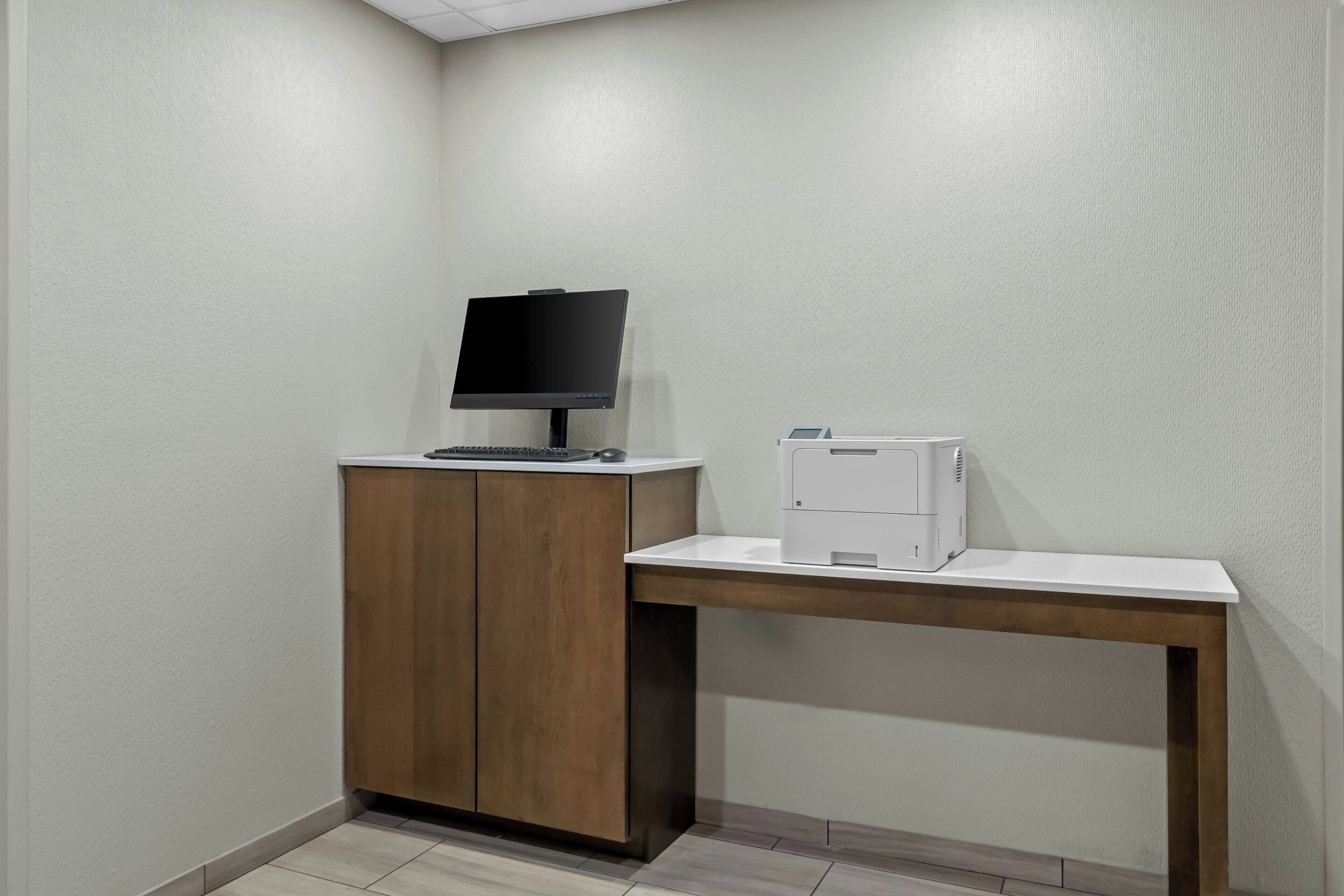 A small office area with a desk, a computer monitor, and a printer.