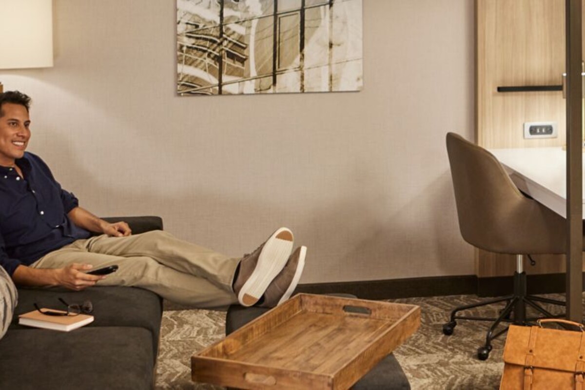 Une chambre d’hôtel équipée d’un canapé, d’un bureau, d’une chaise, d’une table basse en bois et d’un lit.