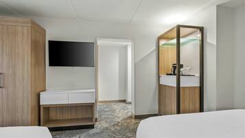 A hotel room with a bed, a desk, a mirror, and a TV.
