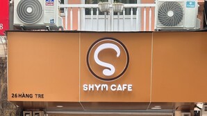 Een winkelgevel met een groot 'S'-logo, dat een Shym Cafe aangeeft.