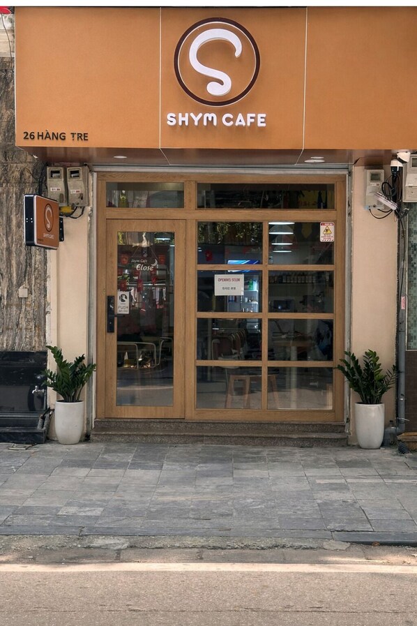 A storefront with a sign reading 'SHYM CAFE' and a sign indicating 'OPENING SOON.'