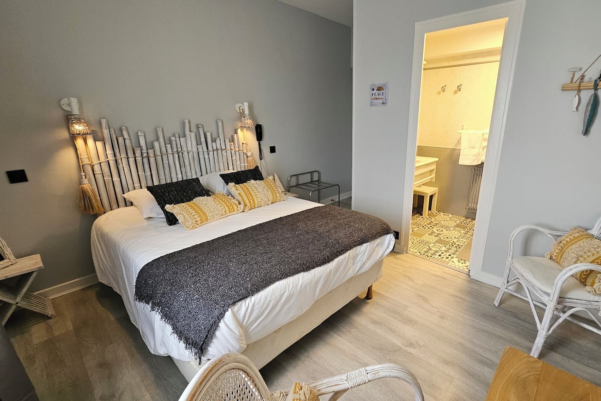 Een slaapkamer met een bed, nachtkastjes, een stoel en een klein tafeltje.