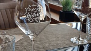 A glass with "Yuberge de la Marine" engraved on it, placed on a woven table mat. - AUBERGE DE LA MARINE (Losne)
