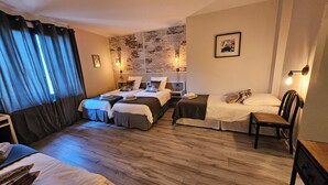 A hotel room with two single beds, a small table, a chair, a wooden floor, a brick wall, and a picture on the wall. - AUBERGE DE LA MARINE (Losne)