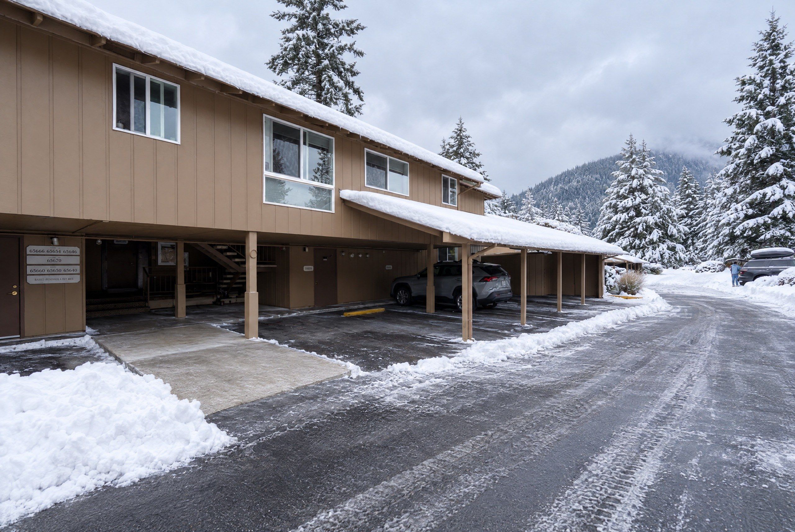 A building with a covered parking area and a snow-covered landscape.