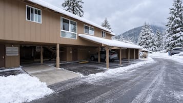 A building with a covered parking area and a snow-covered landscape.