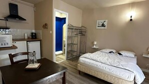 Een compacte kamer met een bed, een klein kitchenette en een eethoek.