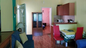 Ein kompakter Wohnraum mit Küchenzeile, einer Essecke mit Tisch und Stühlen sowie einer Sitzecke mit Sofa.