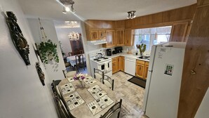 A kitchen with wooden cabinets, a dining table with placemats, and a refrigerator. - Charming 3-bedroom house with WiFi, in Regin, spacious, calm and lovely space  (Regina)