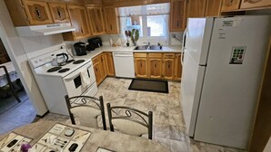 A kitchen with wooden cabinets, a white stove, a sink, and a refrigerator. - Charming 3-bedroom house with WiFi, in Regin, spacious, calm and lovely space  (Regina)