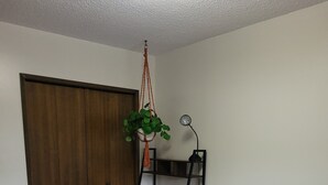 A neatly made bed with a striped bedspread, a bedside lamp, and a plant hanging from the ceiling. - Charming 3-bedroom house with WiFi, in Regin, spacious, calm and lovely space  (Regina)