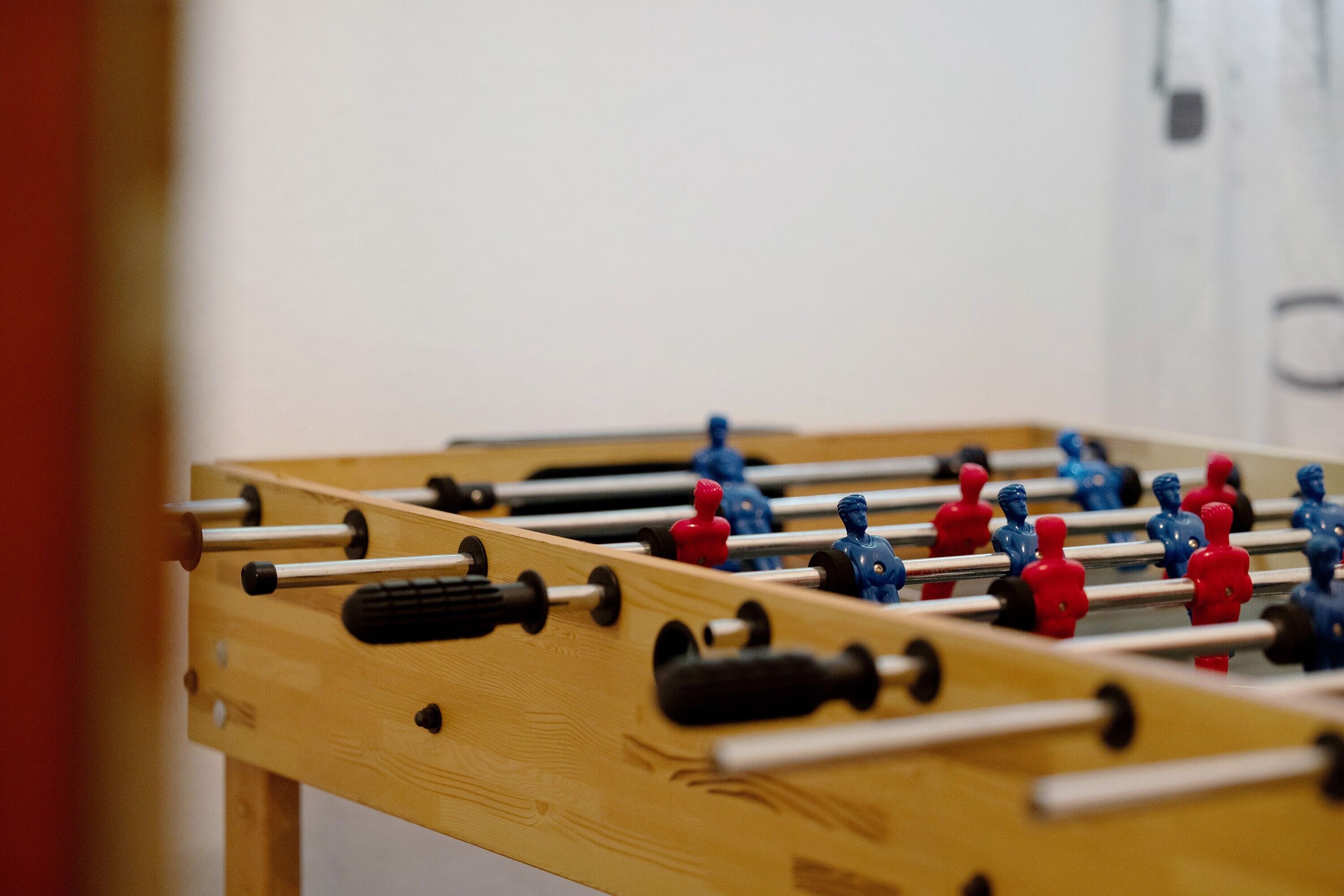 A close-up of a wooden foosball table with red and blue player figures.