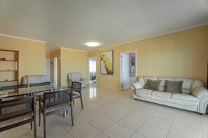 A living room with a glass dining table, two sofas, and a coffee table.