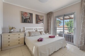 A bedroom with a bed, a dresser, and a large window with a view.
