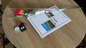 Un tavolo di legno rotondo con un libretto, un portachiavi e una rosa rossa.