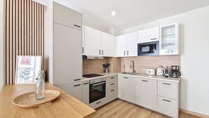 A modern kitchen with white cabinetry, a wooden countertop, a microwave, a coffee maker, and a sink.