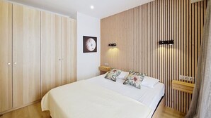 A bedroom with a bed, wooden wardrobe, and a wall-mounted picture.