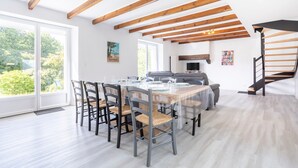 Een eetruimte met een tafel voor vier personen, houten balken in het plafond en een trap aan de rechterkant.