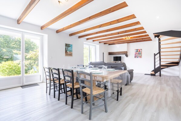 Comedor con una mesa dispuesta para cuatro, vigas de madera en el techo y una escalera a la derecha.
