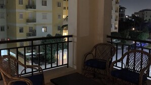 Een balkon met rieten meubilair en uitzicht op omliggende gebouwen.