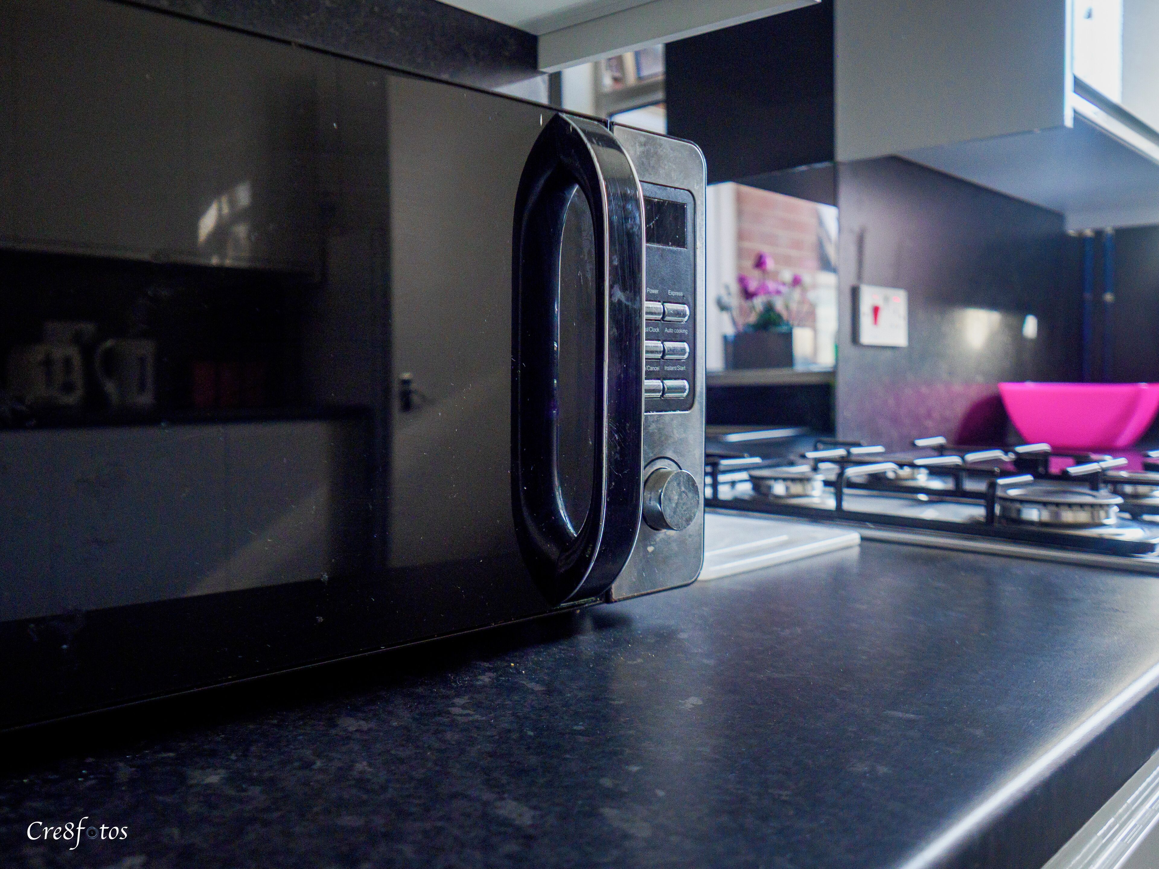 Un forno a microonde su un piano di lavoro della cucina, con una stufa a gas sullo sfondo.