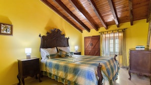 A bedroom with a wooden ceiling, a bed with a plaid bedspread, a nightstand with a lamp, and a wooden dresser. - Holiday Home 'Amarela' with Mountain View, Shared Pool and Wi-Fi (Meca)
