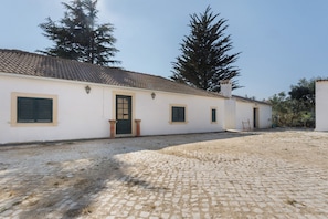 Un bâtiment avec un toit recouvert de tuiles, une porte et des fenêtres équipées de volets.