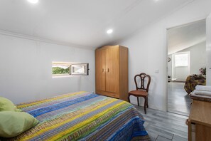 Een slaapkamer met een bed, een houten garderobe, een stoel en een raam.