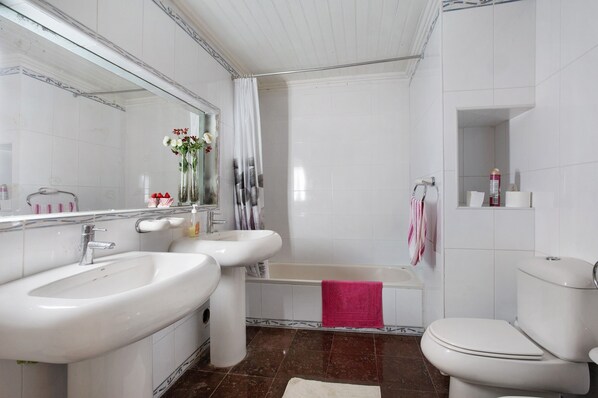 A bathroom with a sink, mirror, bathtub, and toilet. - Holiday Home 'Grande' with Mountain View, Shared Pool and Wi-Fi (Meca)