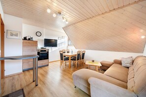 A modern loft with a dining area, kitchenette, and a cozy living space with a sofa and a TV. - Apartment 'Panoramablick' with Mountain View, Shared Terrace and Wi-Fi (Haslach im Kinzigtal)