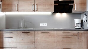 Une cuisine moderne avec des meubles en bois, un évier en acier inoxydable et une machine à café.