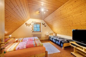 A cozy attic bedroom with a sloped ceiling, a bed with colorful bedding, a second bed, a TV stand, and a window with butterfly decorations. - Apartment 'Panoramablick' with Mountain View, Shared Terrace and Wi-Fi (Haslach im Kinzigtal)