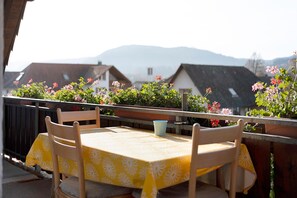 A balcony with a table and chairs, a potted plant, and a view of houses and mountains. - Apartment 'Panoramablick' with Mountain View, Shared Terrace and Wi-Fi (Haslach im Kinzigtal)