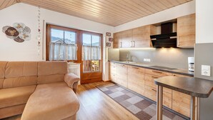 Une cuisine chaleureuse avec des meubles de rangement en bois, un four encastré et une fenêtre agrémentée de rideaux.