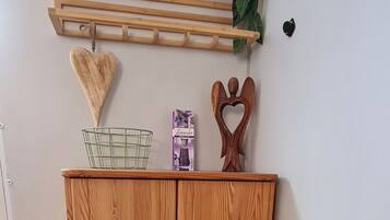 A wooden wardrobe with two doors, a small shelf with a heart-shaped decoration, and a hanging plant.